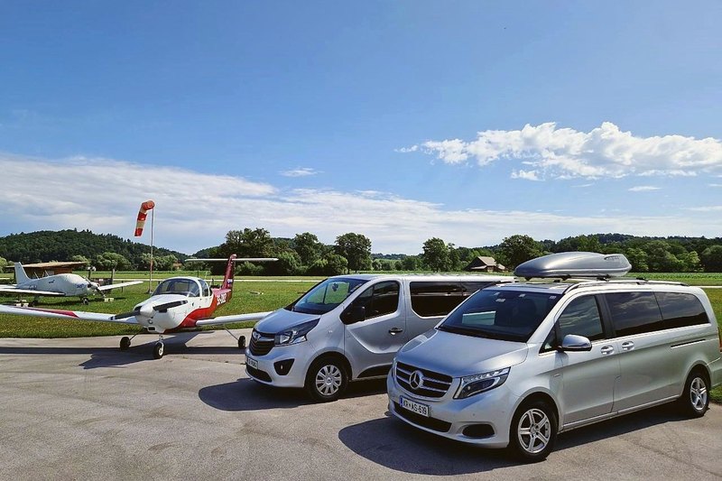Mercedes V-Class with a roof box and an Opel Vivaro next to aircraft at an airfield