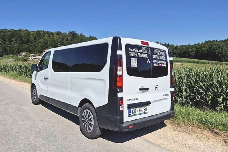White Opel Vivaro from behind, with TourSlo.net Travel Transfer on the rear window